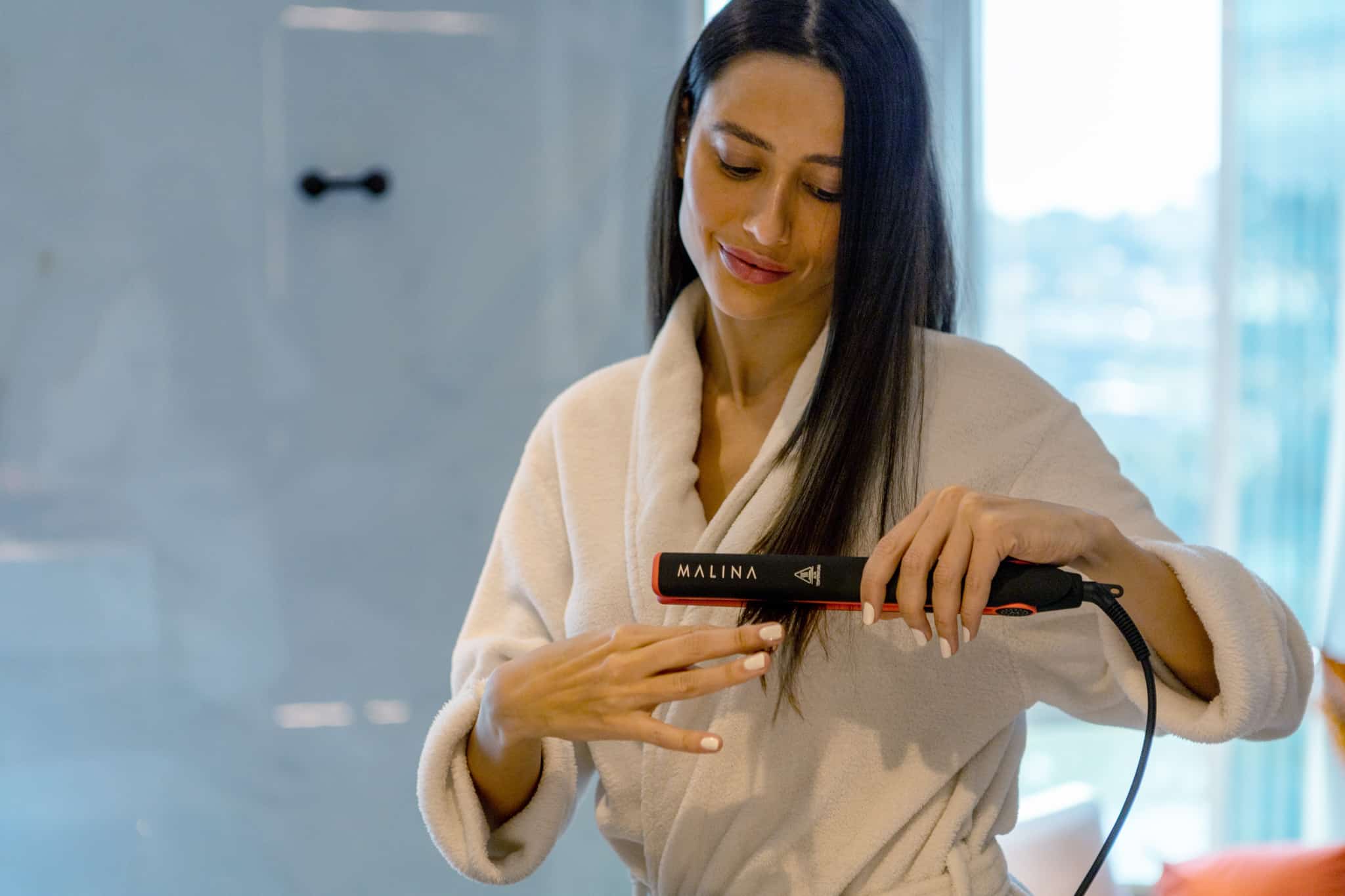 woman curling hair with a malina straightener